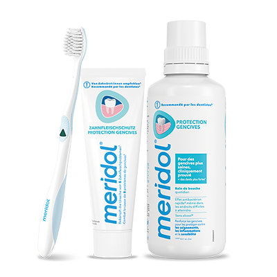 Des flacons de bain de bouche meridol med (CHX 0,2 %) et une brosse à dents blanche à poils bleus.
