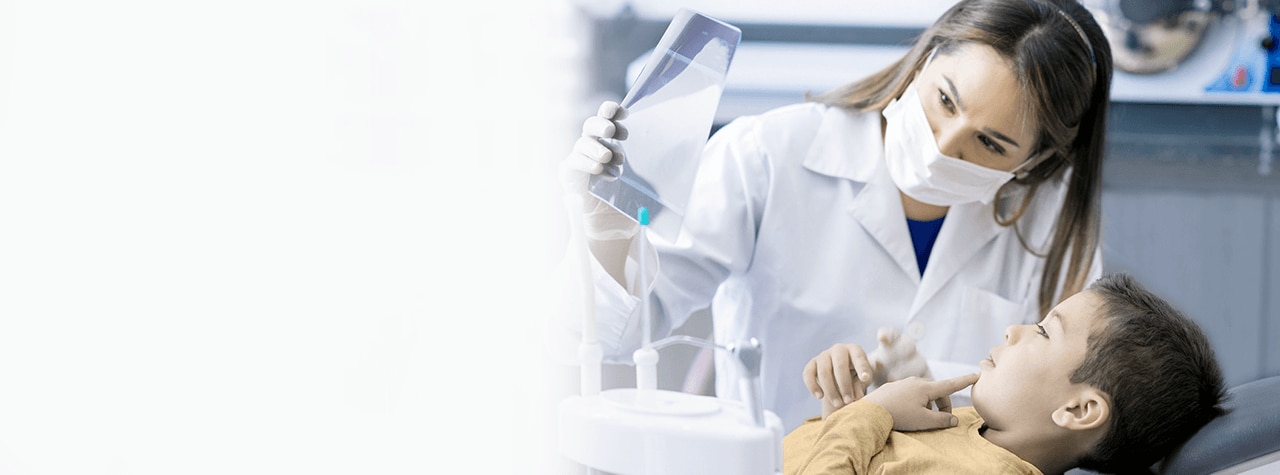 Ein Zahnarzt, der eine PSA-Schutzausrüstung und einen weißen Laborkittel trägt, lächelt mitfühlend